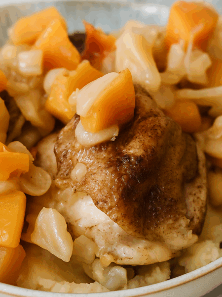 A braised chicken thigh, apple pieces, and squash cubes are shown atop mashed potatoes.