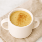 A cup of healthy apple quinoa drink is shown dusted with cinnamon.