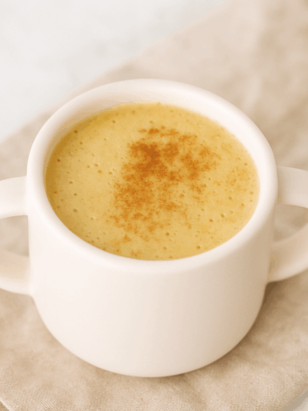 A cup of healthy apple quinoa drink is shown dusted with cinnamon.