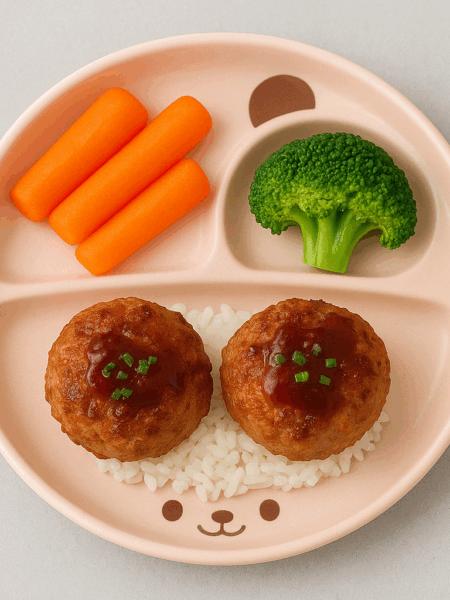 Sample plate of the best meatballs for kids: two lion's head meatballs atop rice, sided by veggies.