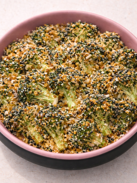 A bowl full of crispy roasted broccoli covered with breadcrumbs and grated parmesan cheese.