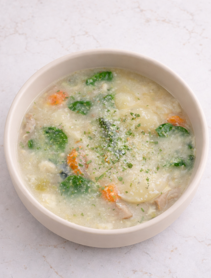 Kid-friendly creamy soup with gnocchi, sausage, spinach, and vegetables in a toddler bowl