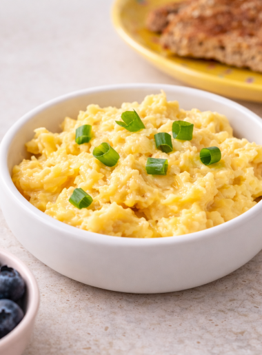 A bowl of soft shirred scrambled eggs for toddlers is sided by toast and fruit.
