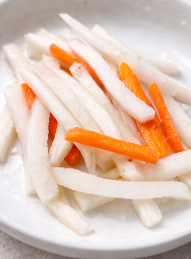 A bowl full of pickled daikon radish and carrot strands is shown as an example of easy vegetables for kids that they'll actually eat.