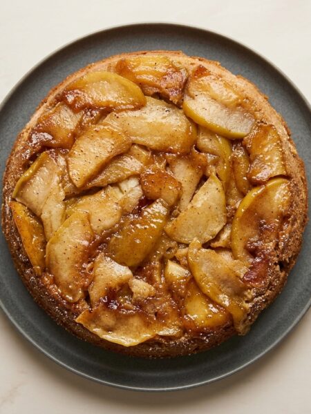 Overhead shot of a full apple upside down cake, with slices of caramelized apple slices dotting the top.